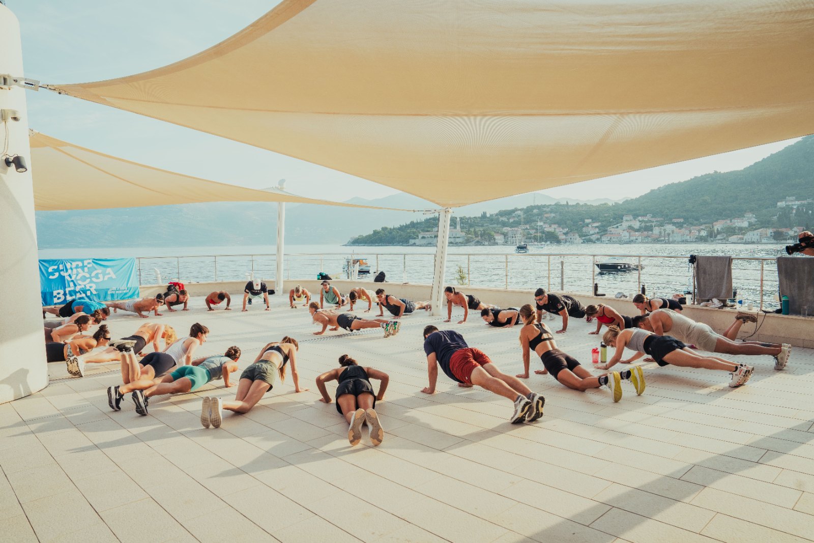 A full SurfYogaBeer group holding planks on a rooftop terrace above the sea in Croatia
