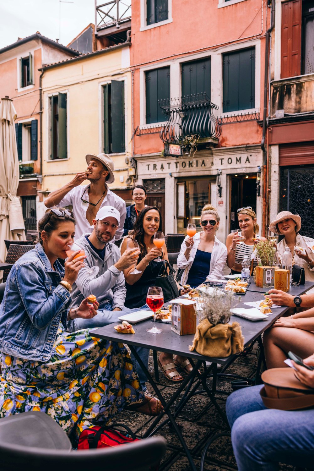 A SurfYogaBeer group toasting spritzes at a long trattoria table